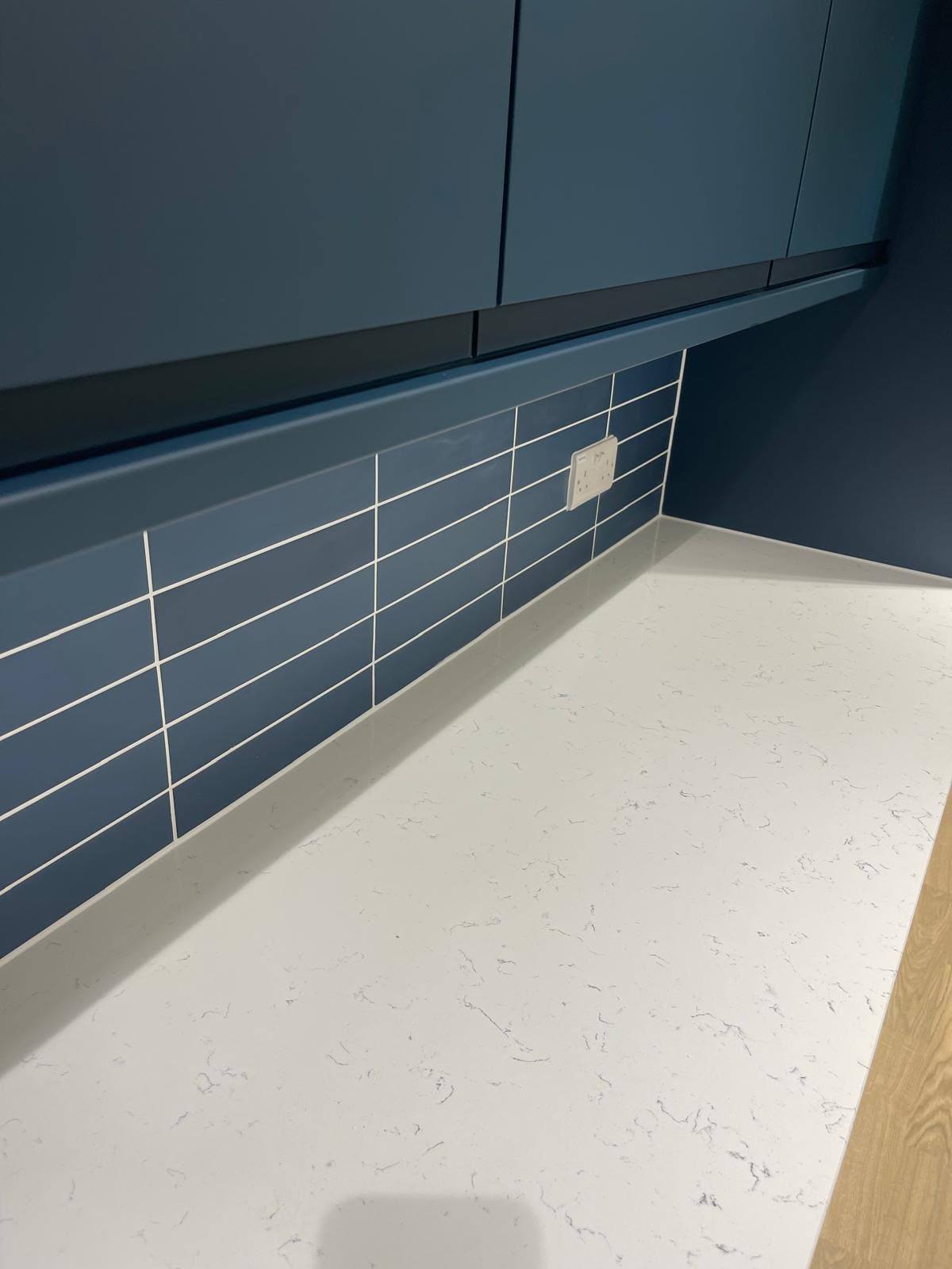 Marble worktop sealed to blue kitchen units and tiled splashback