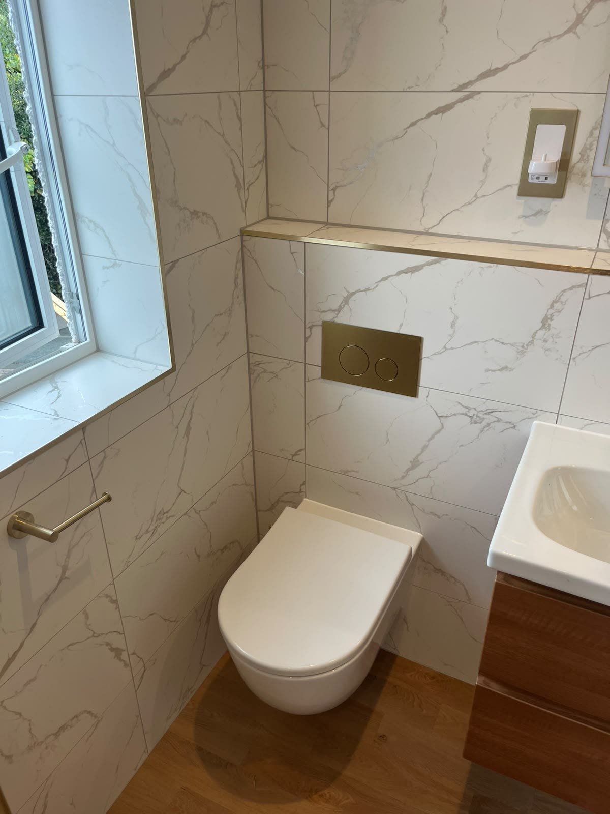 Marble-effect cloakroom with wall-hung WC and window sill neatly silicone sealed
