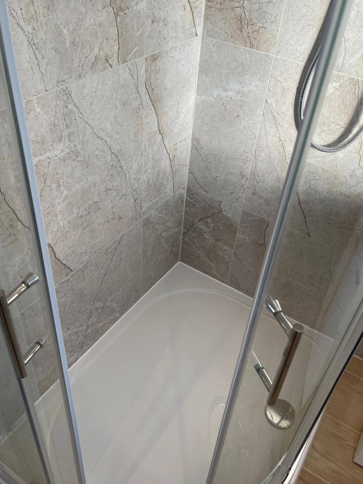Corner shower tray silicone sealed to marble-effect wall tiles