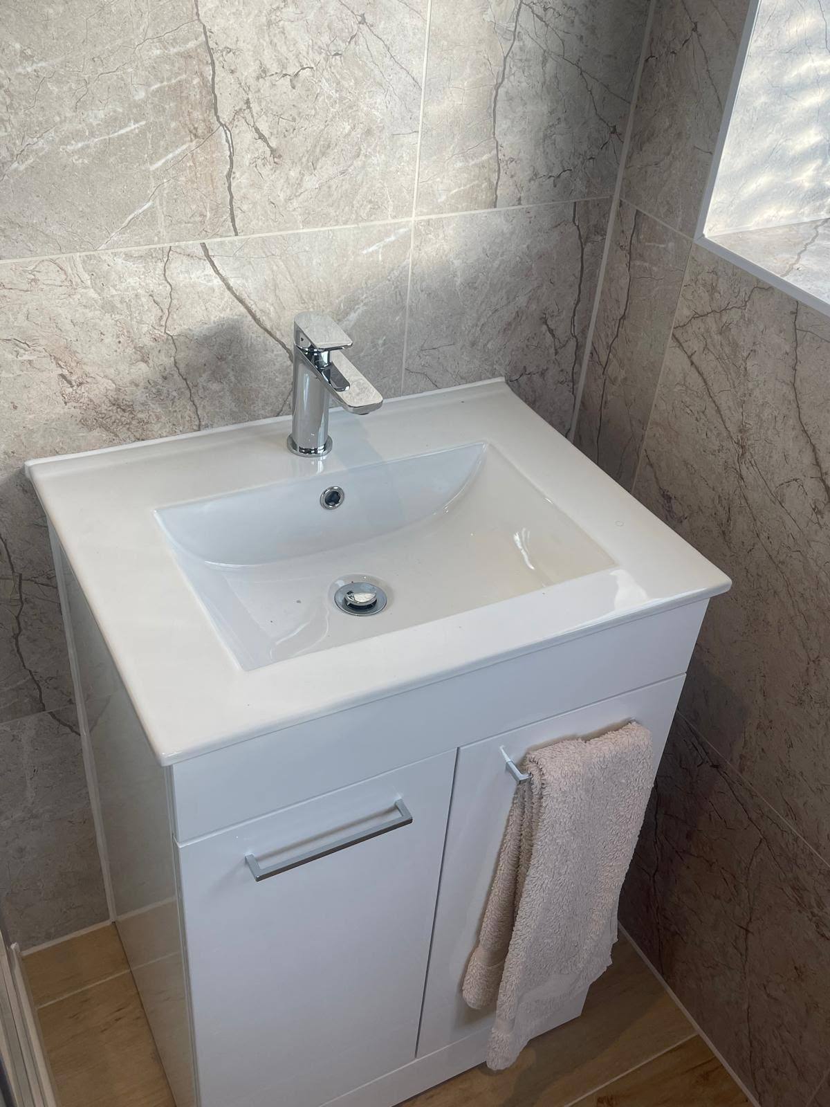 Pedestal basin sealed against marble-pattern bathroom wall tiles