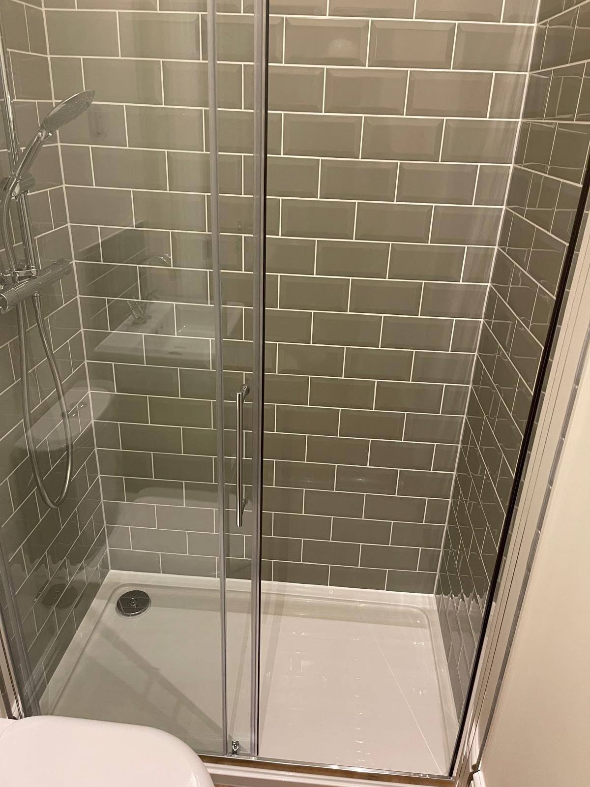 Shower enclosure with sealed tile joints and chrome shower head