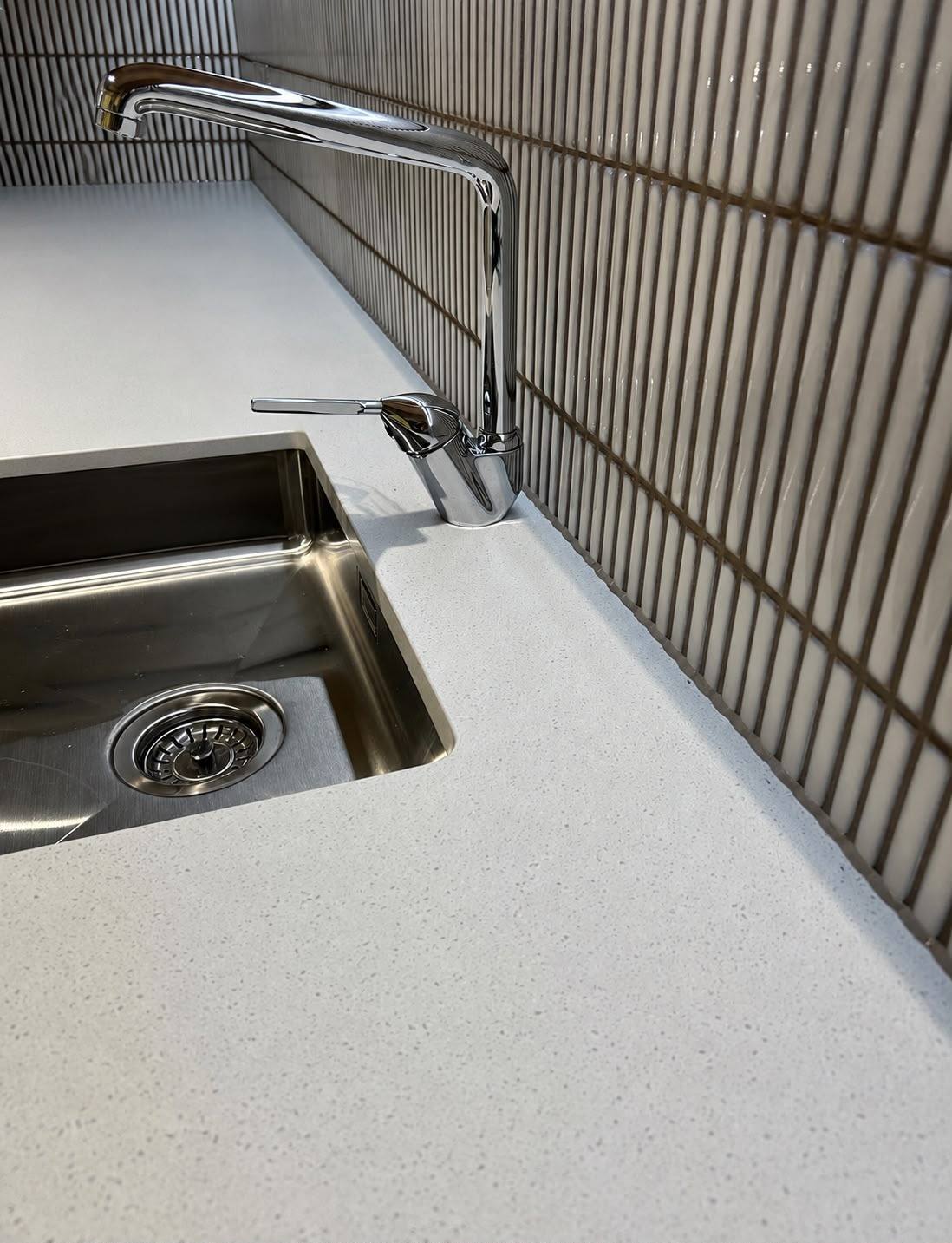 Undermount sink and chrome tap sealed into a kitchen worktop