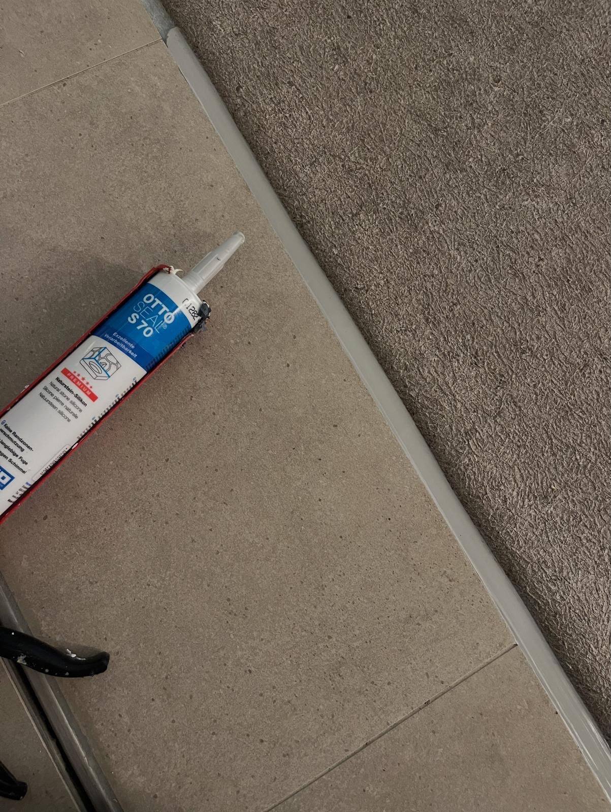 Neutral-cure silicone mastic applied to a stone tile floor-to-wall joint
