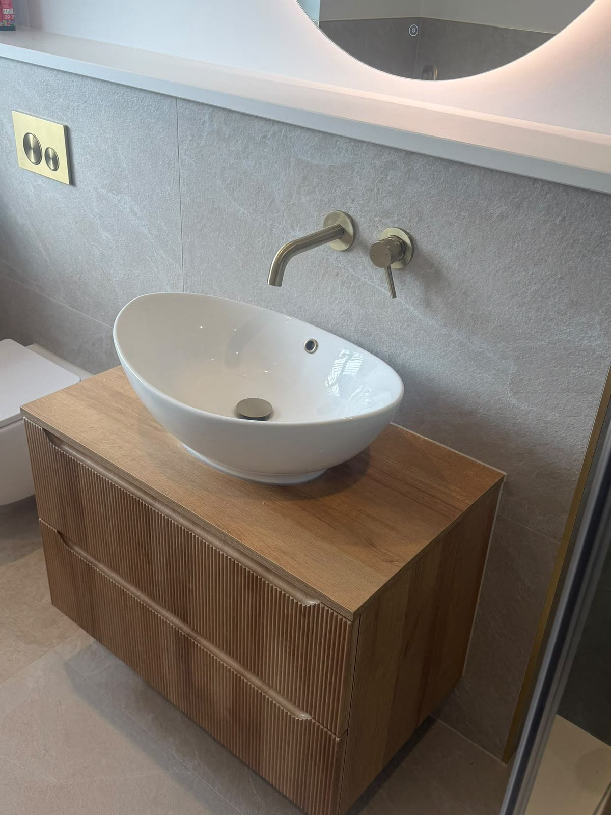 Vessel basin on a fluted oak vanity with clean silicone line to grey tiled wall