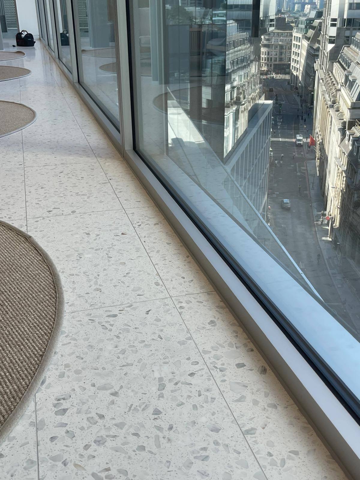 Glass curtain wall sealed to terrazzo flooring with a thin neat silicone joint