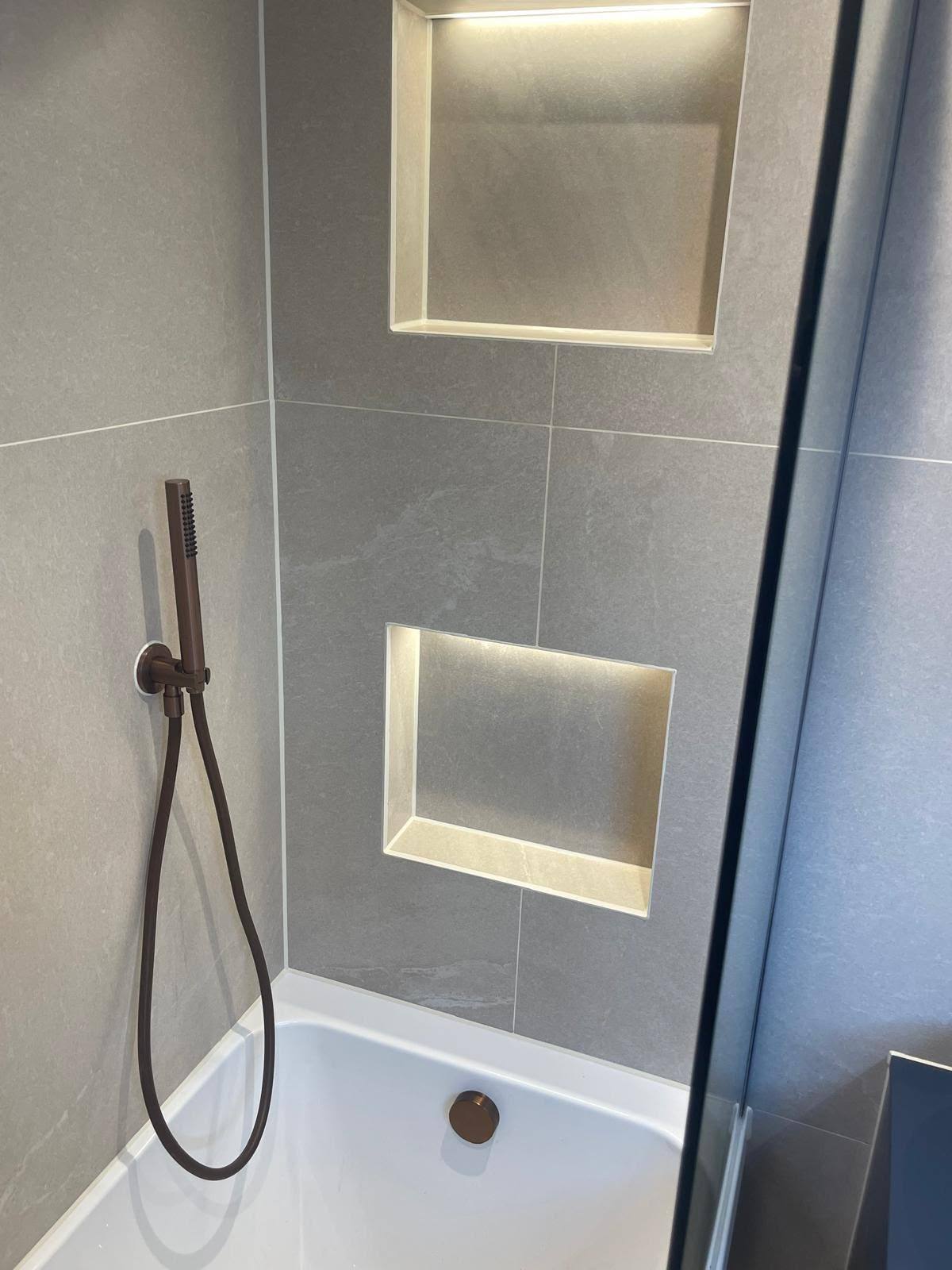 Bath and shower with sealed illuminated tile niches and bronze fixtures