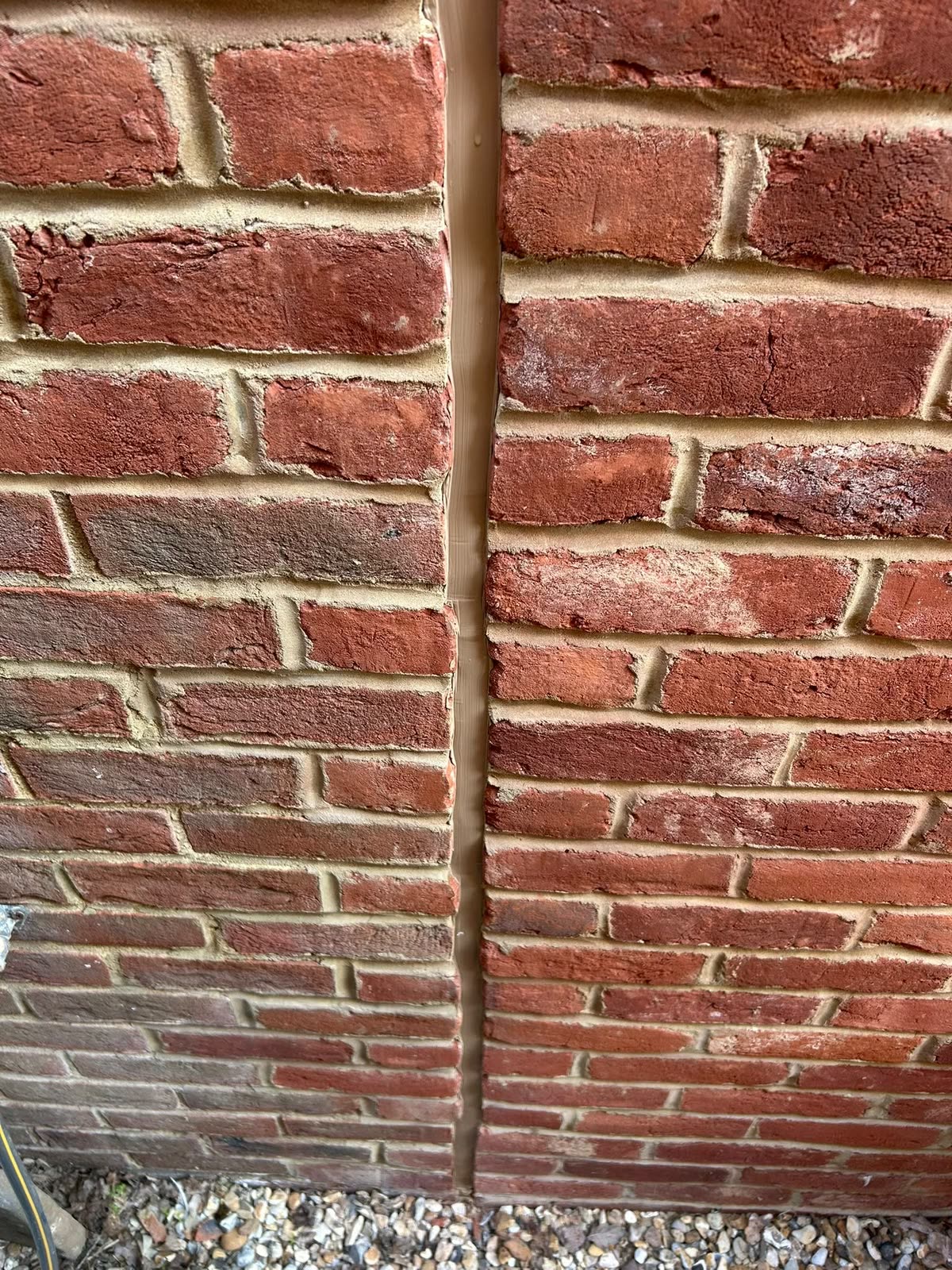 Vertical expansion joint in red brickwork sealed with colour-matched sealant